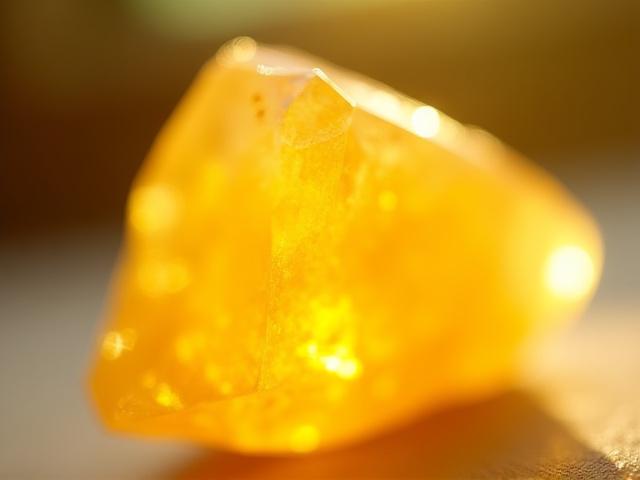 Egy fényes sárga citrin kristály, arany árnyalatokkal, természetes fénnyel megvilágítva.